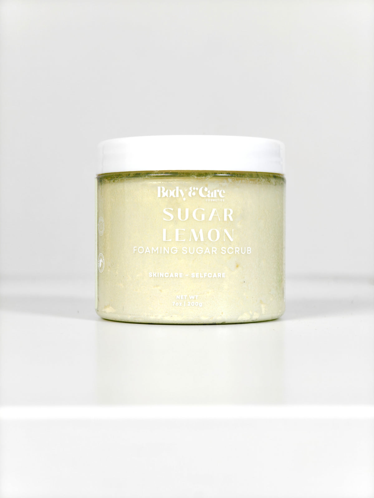 Body & Care Sugar Lemon Foaming Sugar Scrub in a clear jar with white lid on a white background.
