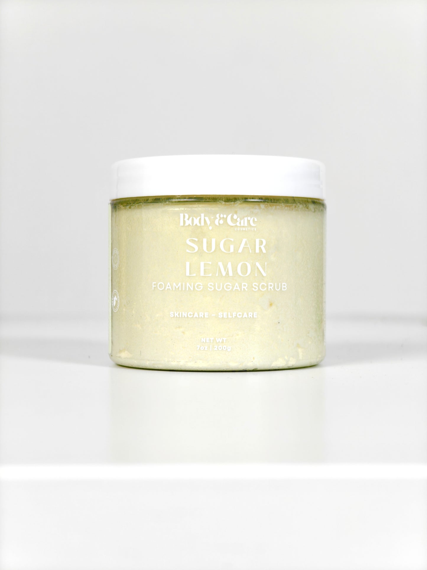 Body & Care Sugar Lemon Foaming Sugar Scrub in a clear jar with white lid on a white background.
