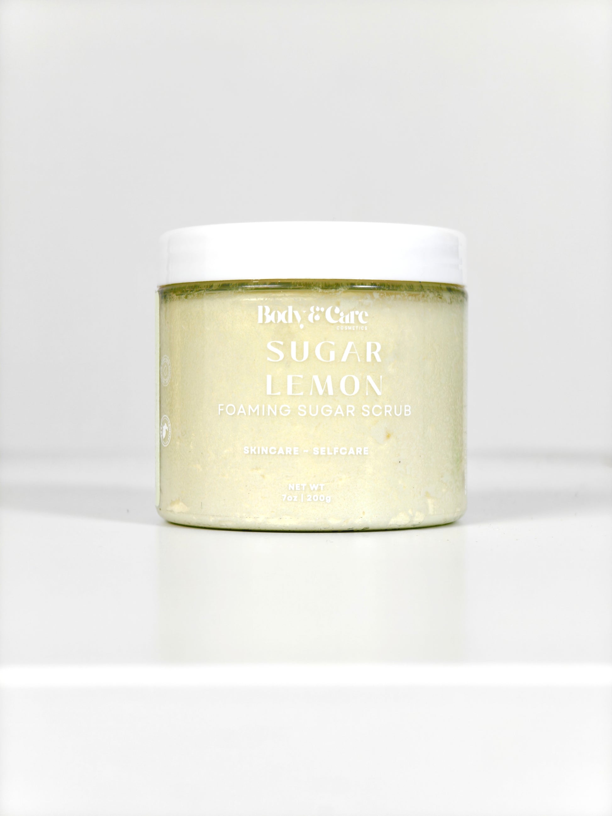Body & Care Sugar Lemon Foaming Sugar Scrub in a clear jar with white lid on a white background.