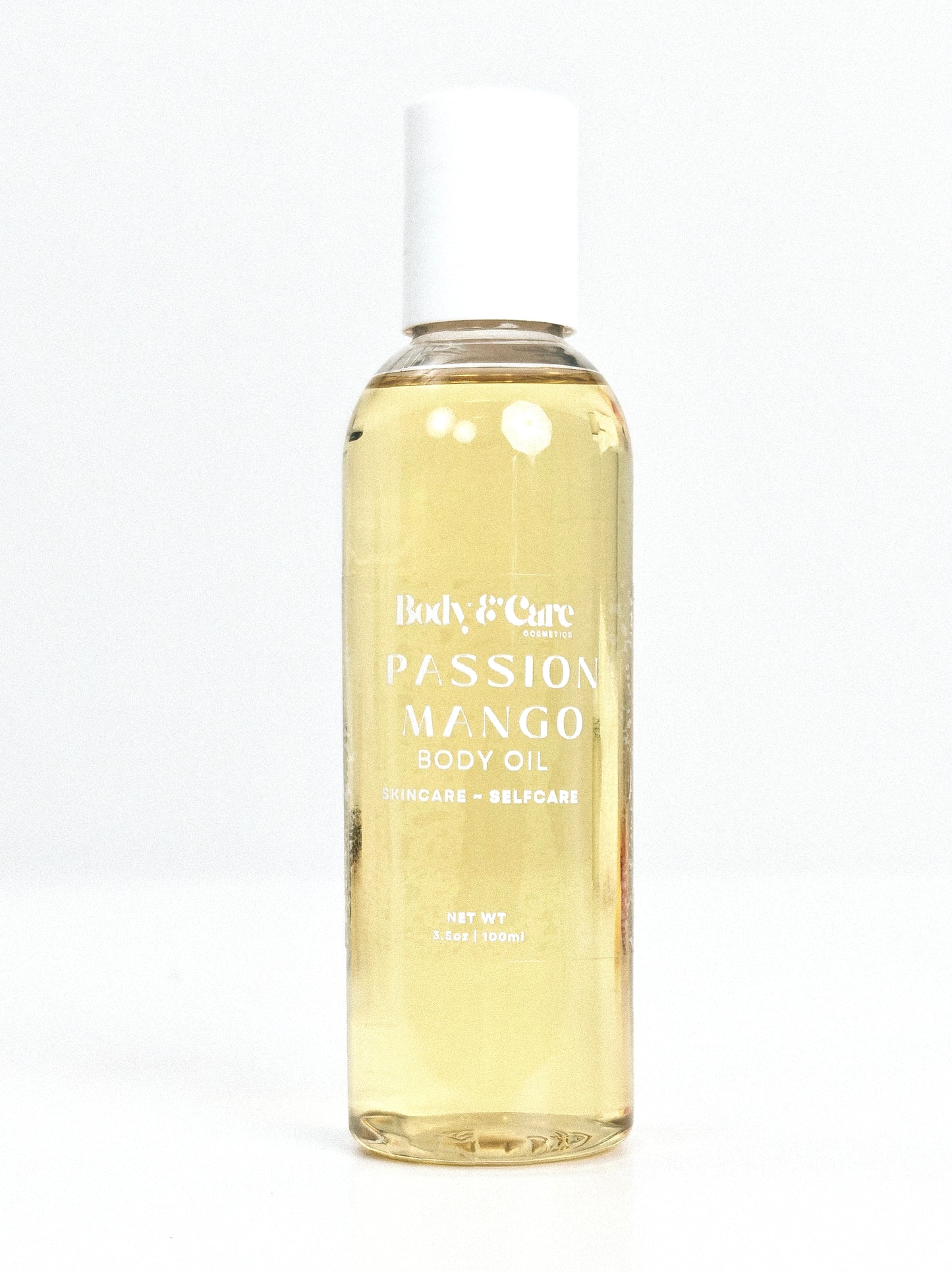 Body & Care Passion Mango Body Oil in a clear bottle with white cap on a white background.