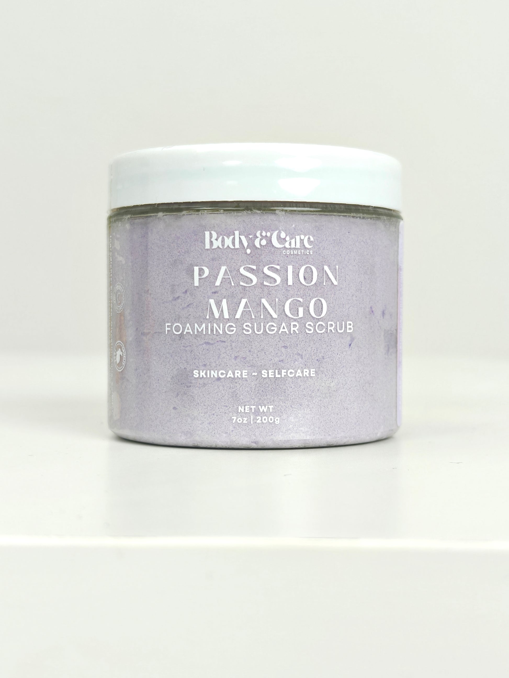 Body & Care Passion Mango Foaming Sugar Scrub in a clear jar with white lid on a white background.