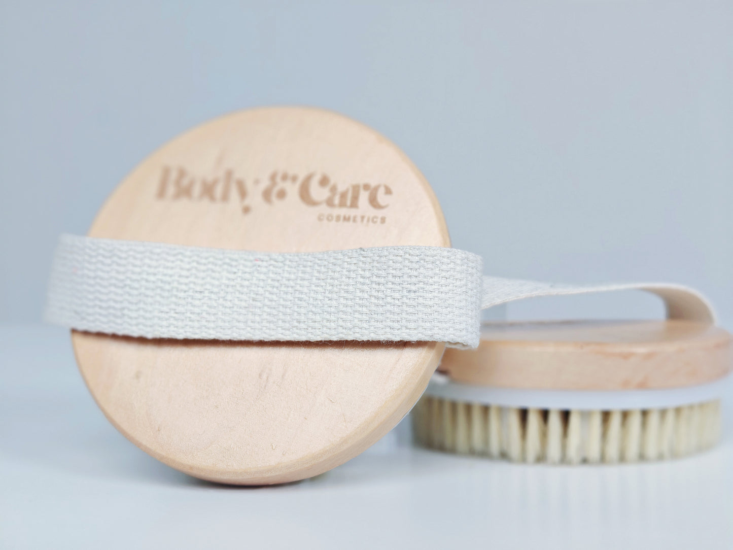 Body & Care wooden body brush with cotton hand strap, shown on a clean white background.